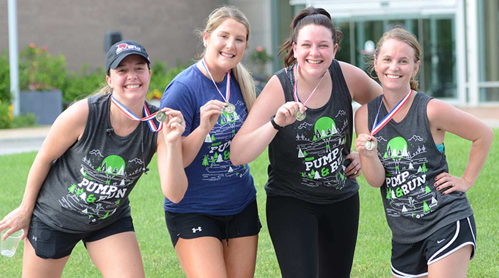 Four female athletes showing off medals in Pump and Run t-shirts.