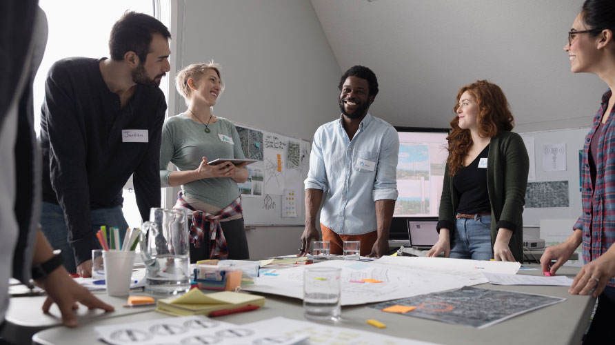 A team of employees standing around a conference room table collaborating