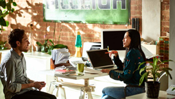 Man and woman talking at a desk in an office