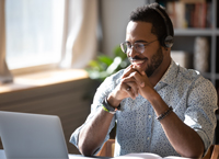 Smiling young man works on a laptop at home