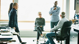 Group of employees speak together in a brightly lit office