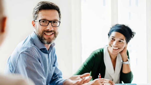 Smiling man and woman talk at a table in an office