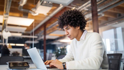 Young man works at a laptop in a modern office