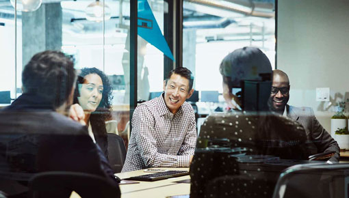 A smiling group of employees talks together during a meeting