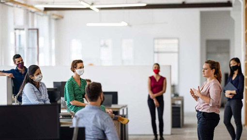 A group of coworkers meet, socially distanced, and wearing masks