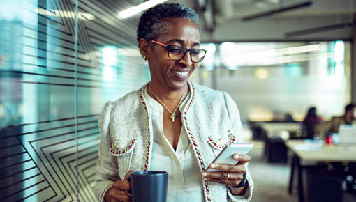 A smiling business woman checks her cell phone in her office