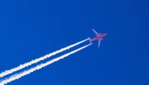 Commercial airline jet flies against a dark blue sky