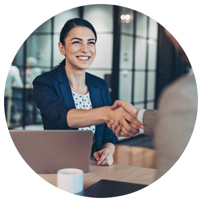 Smiling young woman shakes hand with coworker in office