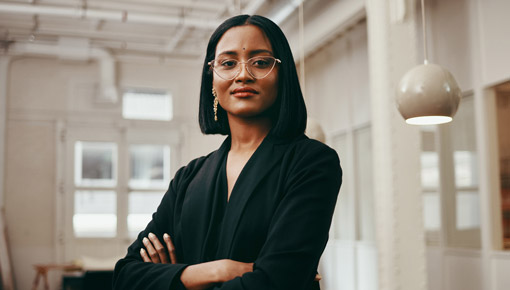 A young professional woman confidently smiles and crosses her arms