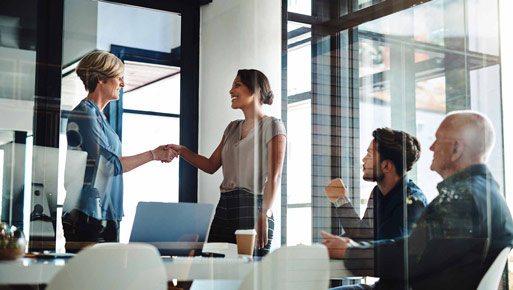 Two women shake hands during a business meeting