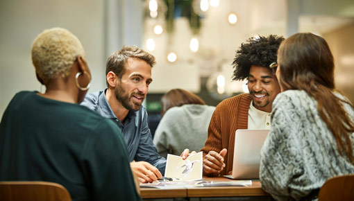 Four coworkers sit and talk at a table