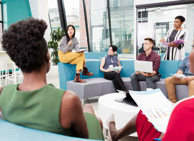 A group of coworkers gather on couches to talk together