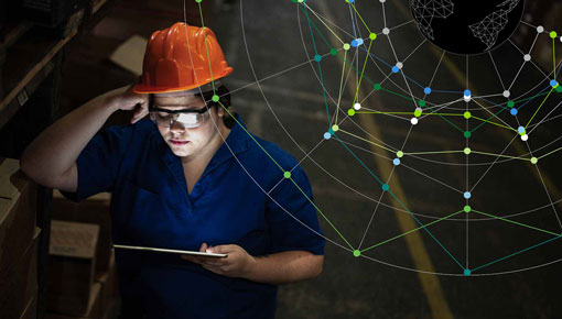 A woman with an orange hardhat and glasses uses a tablet computer, with an overlay of a brightly lit network graphic.