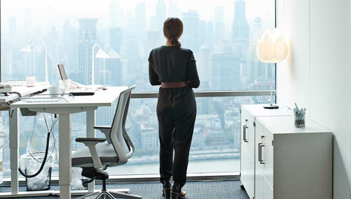 A woman with dark hair looks out her office window