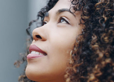 A young woman smiles and looks upward