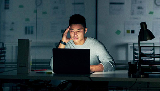 A young man looking at his computer screen in the dark.