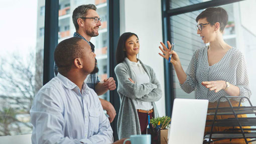 A young woman speaks to a group of coworkers in an office