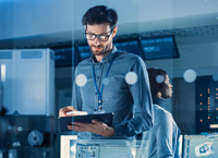 Young white man with glasses uses tablet computer in office