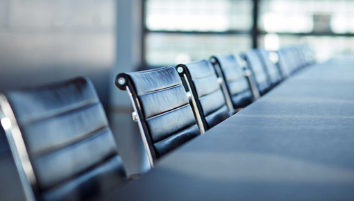 An up close shot of a row of empty chairs in a board room