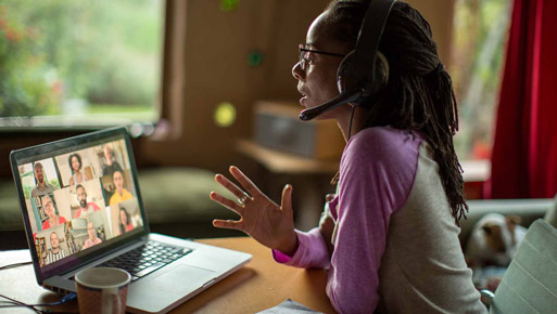 Young business woman with headset speaks during conference call on a laptop computer