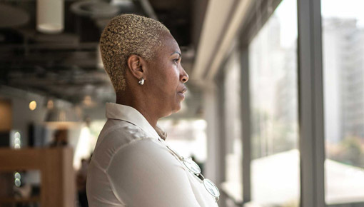 A woman with cropped hair looks out an office window