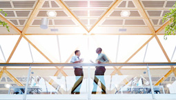 Two business men talk on the balcony of a large office building