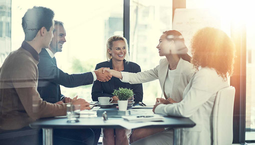 Business colleagues shake hands at a conference table