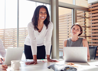 Two women smile at a table in an office