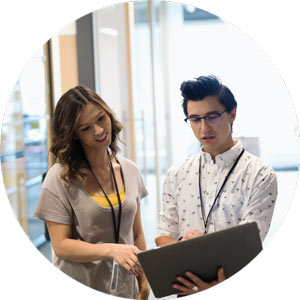 Young man with glasses shows young woman something on computer screen