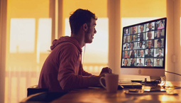 Young man attends video conference at his desktop computer