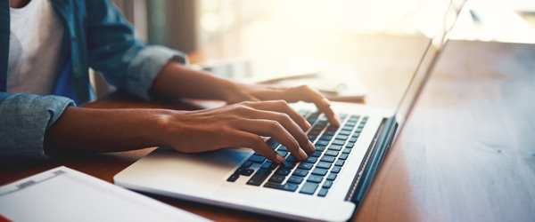 Individual typing on a laptop