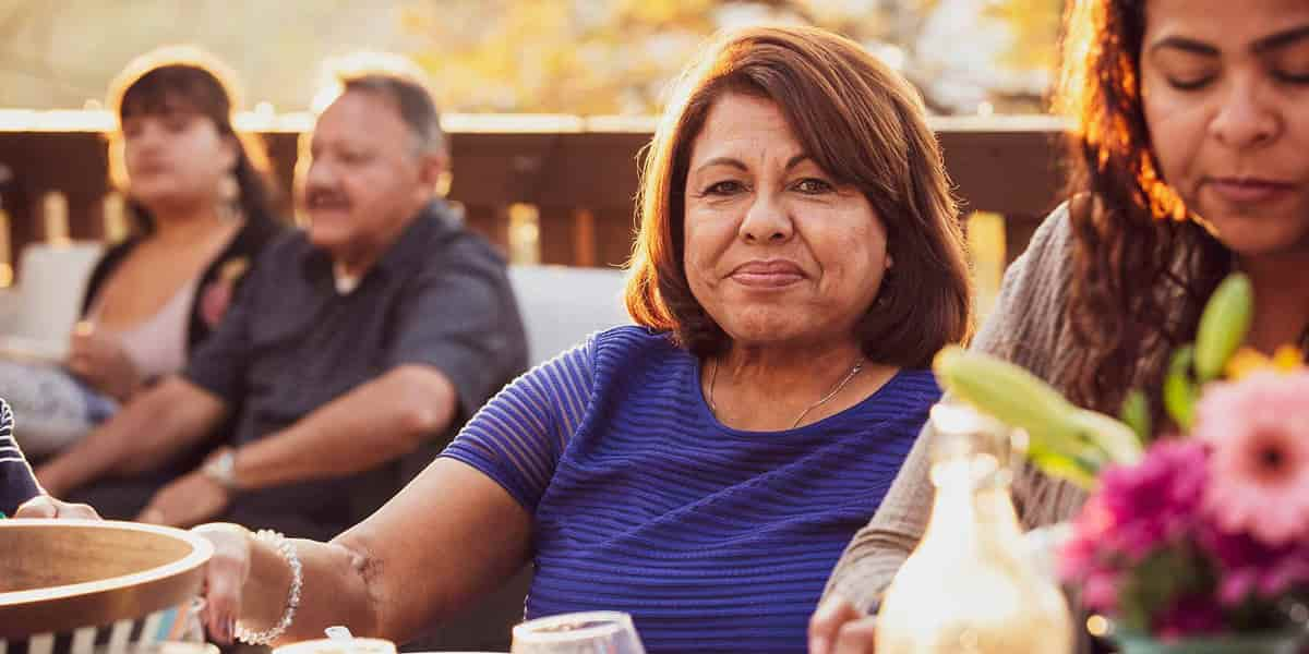 Latino Woman sitting on a patio with other people