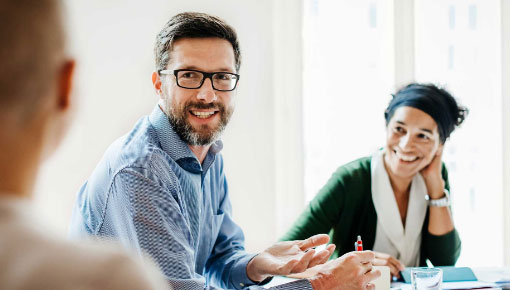 A woman and two men in business attire sitting at a table having a conversation.