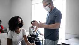 Masked student and staff having a conversation in classroom setting