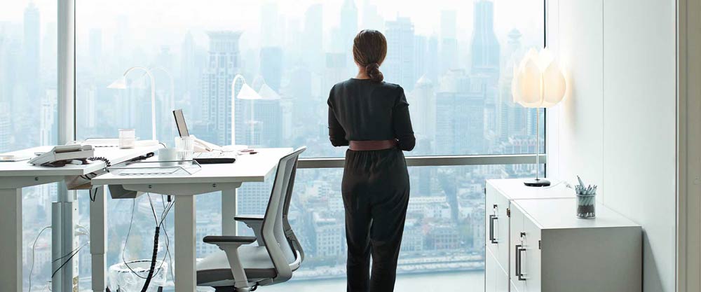 Woman looking at city from office window