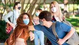 Two students with masks on bumping elbows