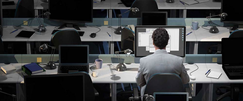 Man sitting alone at a computer in a room full of computers.