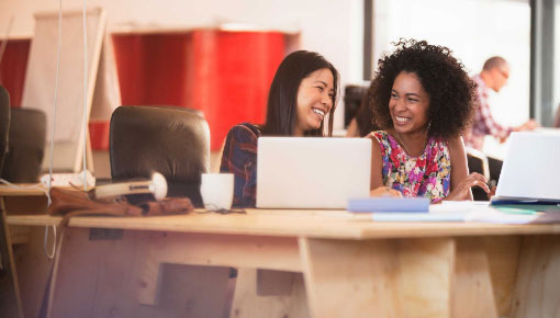 Two women looking at a computer screen smiling.