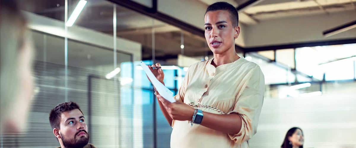 Pregnant woman talking to group of people.