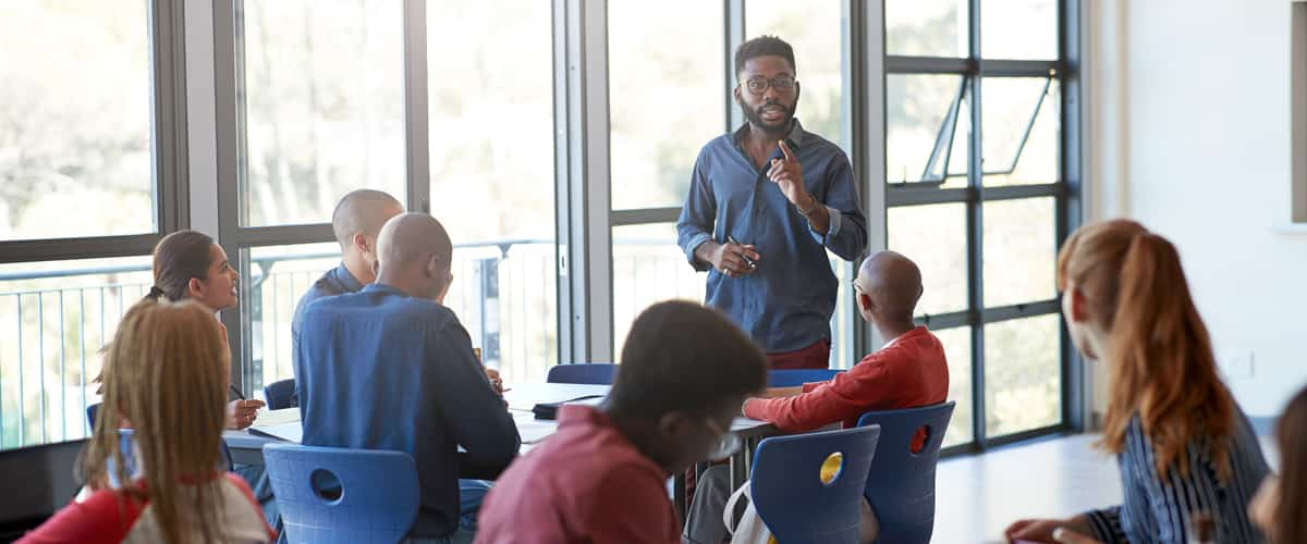 An man talking in front of a group of people sitting at