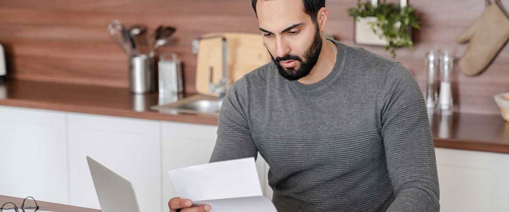 Man reading letter in kitchen.