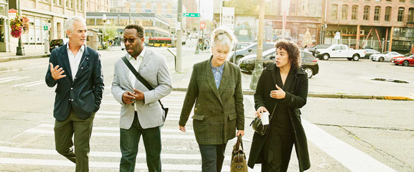 Four people walking down the street having a conversation.