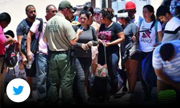 Group of people huddled together outside talking to a U.S. border patrol officer.