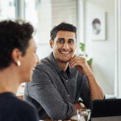 A male employee smiling and talking with a female coworker.